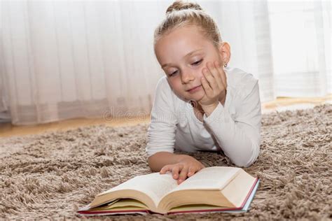 Fille Mignonne Qui Lit Un Livre Sur Le Plancher De Salon Image Stock