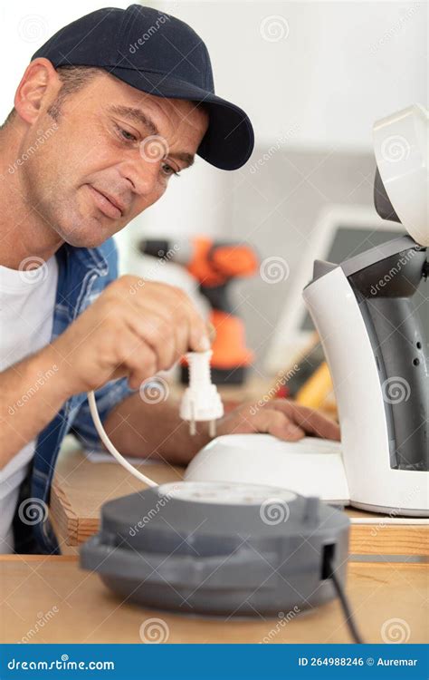 Serious Man Repairing Broken Coffee Machine Holding Plug Stock Photo