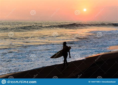 Silhueta Do Surfista Que Anda Na Praia Por Do Sol Imagem Editorial