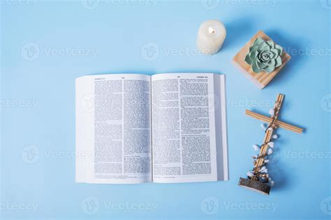 Open Holy Bible With Cross Candle Flame And Decorative Flower On Blue