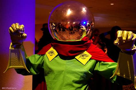 a person dressed in costume holding up their hands and wearing an eyeball helmet with both hands