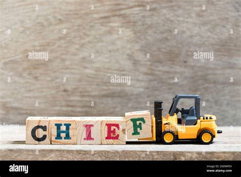 Toy Forklift Hold Letter Block F In Word Chief On Wood Background Stock