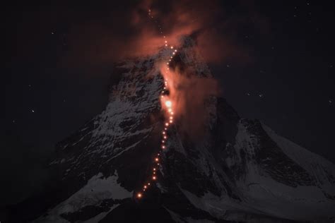 The Matterhorn Lit Up at Night by a Trail of Hikers