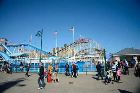 Many People Are Walking Around In Front Of The Roller Coaster