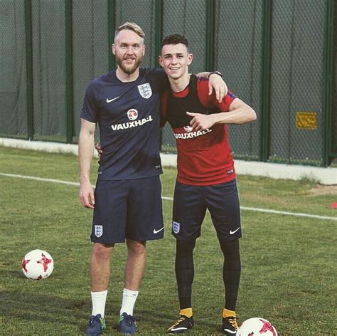 Two Men Standing Next To Each Other On A Soccer Field