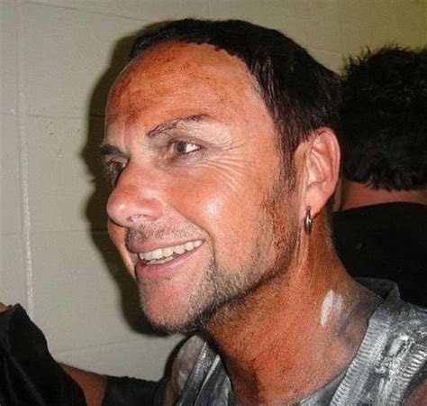 A Man With Mud All Over His Face And Chest Smiles At The Camera While