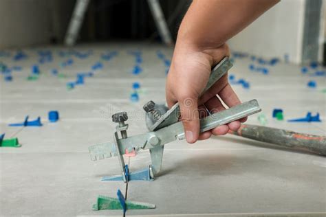 Man Installing Colorful Wedges With Plier On Tiles Closeup Stock Photo