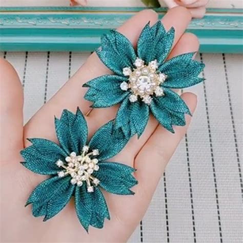 Two Blue Flower Brooches With Pearls On Them In Front Of A Photo Frame