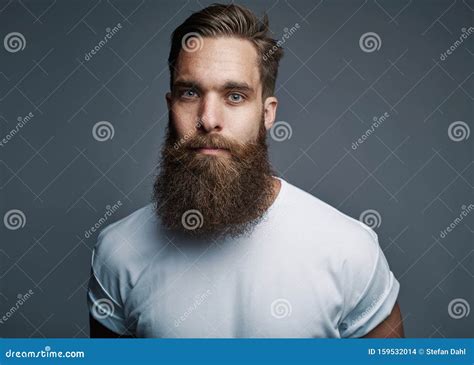 Bearded Young Man Standing Confidently Against A Gray Background Stock