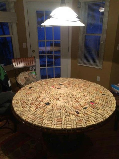 a table made out of wine corks with a lamp on it in front of a window