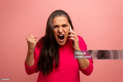 Portrait Of Angry Middle Aged Woman Screaming On Mobile Phone Isolated