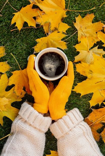 Premium Photo Woman Hands Hold A Cup Of Coffee Next To Yellow Maple