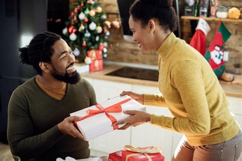 Feliz casal negro trocando presentes de natal em casa Foto Grátis