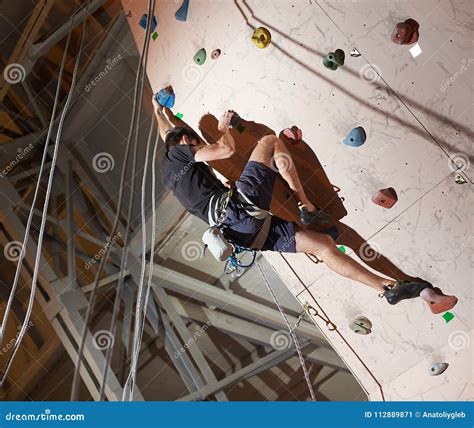 Muscular Man Practicing Rock-climbing on a Rock Wall Indoors Stock ...