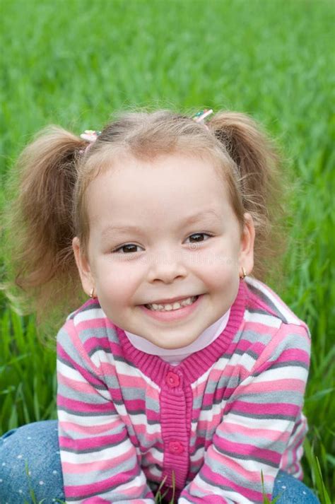 Petite Fille De Sourire Se Trouvant Sur Lherbe Verte Image Stock