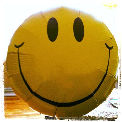 a large yellow smiley face balloon sitting on top of a wooden floor next to a window