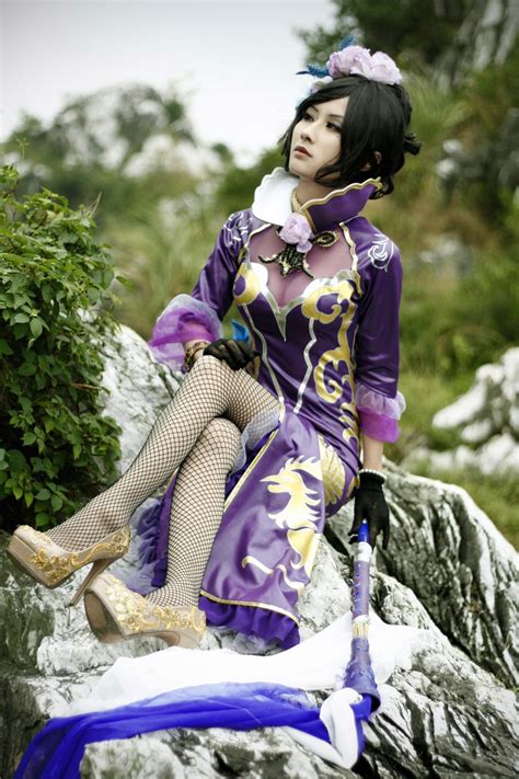 a woman sitting on top of a rock wearing a purple dress and holding an ...