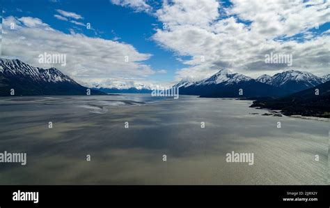 An Aerial View Of A Snowy Mountain Range Covered With Clouds Against A