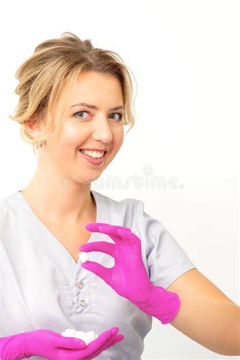 Portrait Of A Young Smiling Caucasian Beautician Wearing Pink Gloves