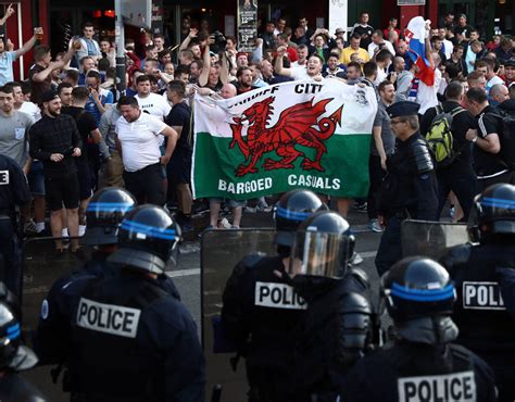 Welsh Football Fans Hold Up A Flag As Supporters Gather Outside A Pub