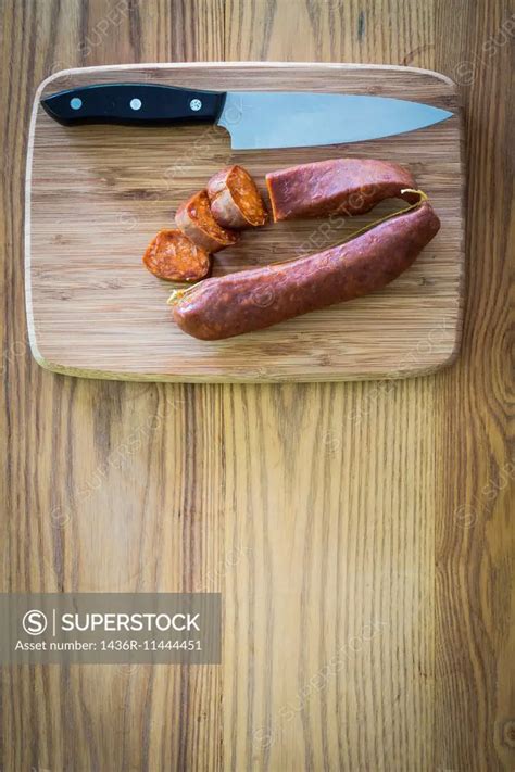 Chorizo Sausage Cut Into Pieces On A Wooden Cutting Board With Knife Next To It Superstock