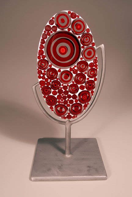 A Red And White Sculpture With Circles On Its Face Sitting On A Metal Stand