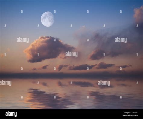 Moon with sunset sky reflected in water surface Stock Photo - Alamy