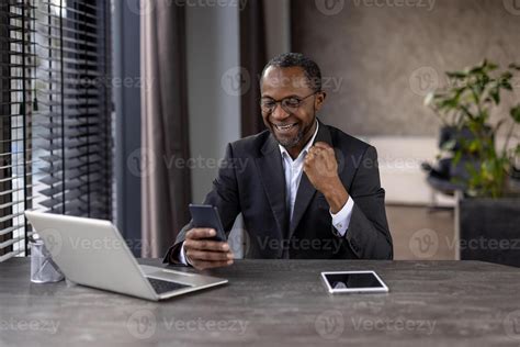 A Smiling African Businessman Celebrates Success While Using His