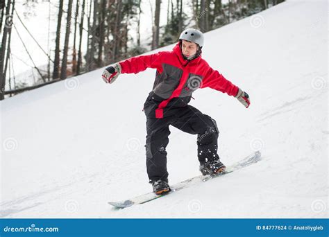 Male Snowboarder Riding Down From The Mountain In Winter Day Stock