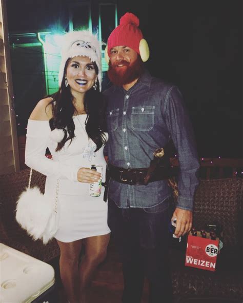 A Man Standing Next To A Woman In A White Dress And Santa Claus Hat On