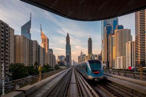 Dubai metro train entering the station with background of high rise ...