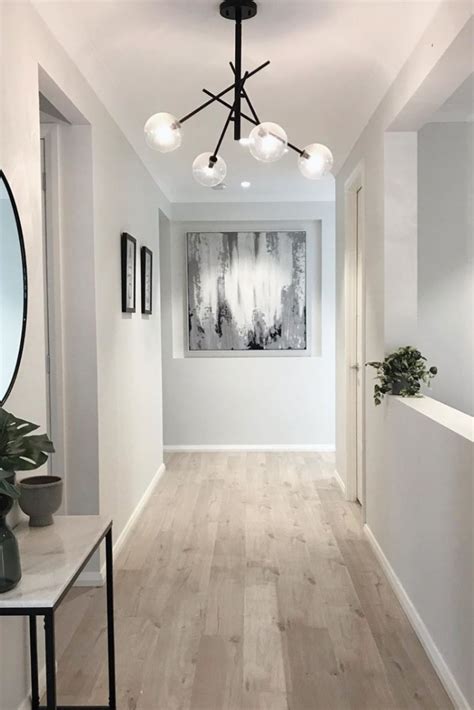 A Long Hallway With White Walls And Wood Flooring Is Lit By Modern