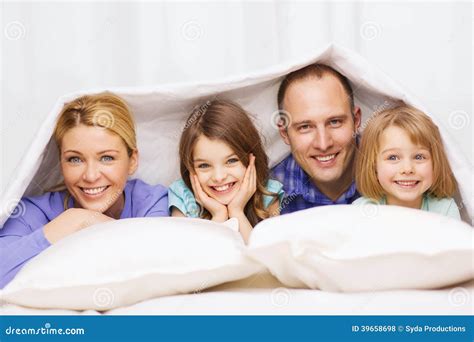 Familia Feliz Con Dos Niños Debajo De La Manta En Casa Foto de archivo