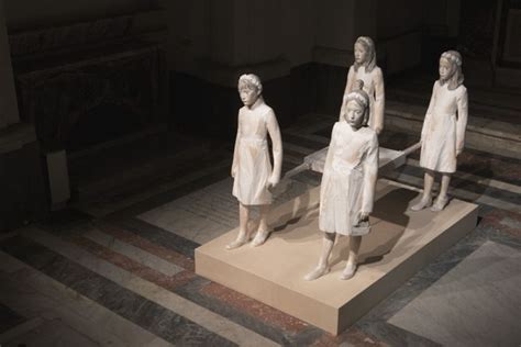 Four Statues Of Women Standing On Top Of A Platform In A Room With