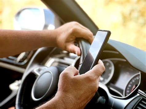 Mãos do homem segurando um celular enquanto dirige distração ao volante