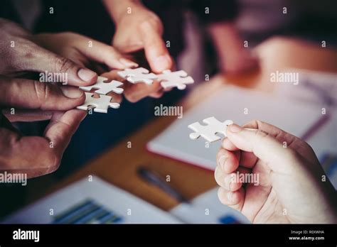 Team Placing Four Puzzles Jigsaw Together For Team Concept Stock Photo