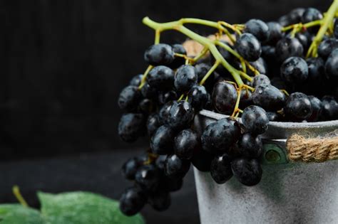 Um Balde De Uvas Pretas Folhas Em Fundo Escuro Foto De Alta