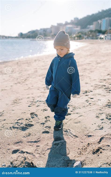 Little Girl Walks Along the Sandy Beach, Looking at Her Feet Stock ...