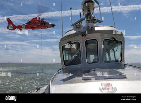 A trail line is lowered from a USCG MH-65 Dolphin helicopter as it ...