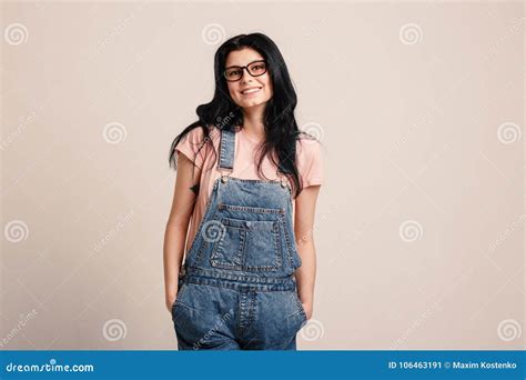 Beautiful Smiling Brunette Girl Wearing Glasses In Denim Overall Posing