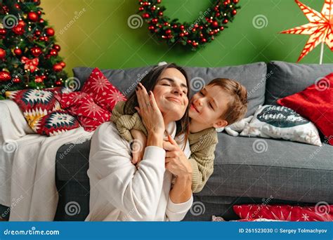 Mother Sitting On A Sofa With Her Son In Living Room Decorated For