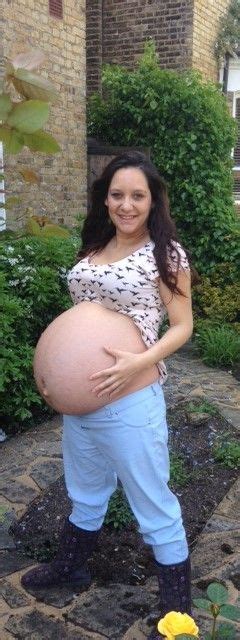 A Pregnant Woman Standing In Front Of A House With Her Belly Exposed