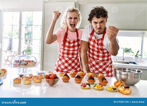 Couple Of Wife And Husband Cooking Pastries At The Kitchen Angry And Mad Raising Fist Frustrated