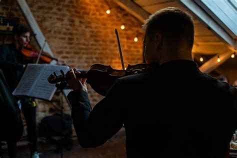 Un hombre toca el violín en una habitación oscura con luces que cuelgan