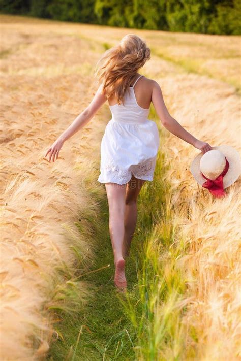 Jeune Fille Blonde Heureuse Dans La Robe Blanche Avec Du Th Courant De Chapeau De Paille Photo