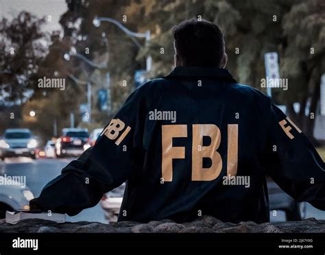 Male Fbi Agent Wearing Dark Blue Coat With Fbi Logo Looking Down The