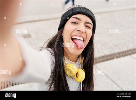 Latina Taking A Selfie With Her Smart Phone Sticking Out Her Tongue And Winking Hispanic Woman