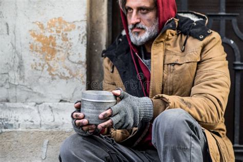 Homeless Beggar Man Sitting Outdoors In City Asking For Money Donation