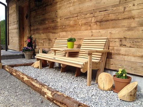 Two Wooden Benches Sitting Next To Each Other In Front Of A Building