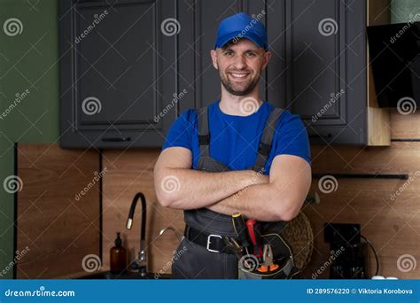 Smiling Handsome Plumber Standing With Crossed Arms And Looking At